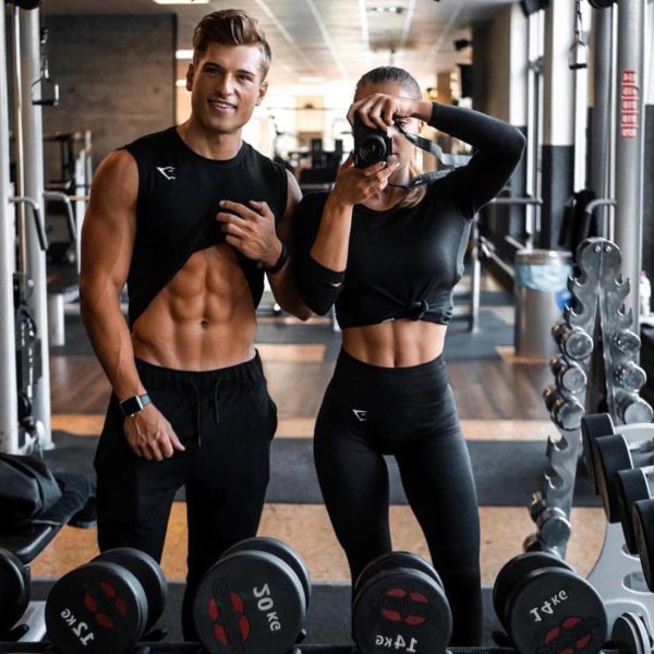 Pareja de hombre y mujer en un gimnasio terminando su rutina diaria y preparandose para tomar un batido para aumento de masa muscular